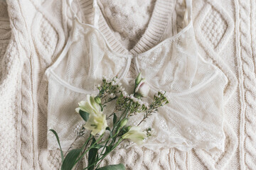 Stylish lace lingerie and spring flowers on sweater. Soft trendy image. Woman essentials, fragrance