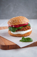 Vegan burger made with red beans, red pepper, spinach and white yoghurt. Fresh delicious vegetarian burger on a cutting board.