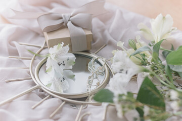 Happy Womens and Mothers day. Stylish gift, jewelry, spring flowers on boho mirror on soft fabric