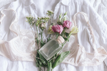 Stylish lingerie, jewelry, perfume and spring flowers on shirt. Soft trendy image. Woman essentials