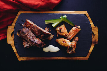 Top view of juicy barbeque pork ribs and dry chicken wings with glaze and hot sauce