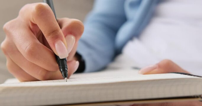 Hands of woman writing notes in diary