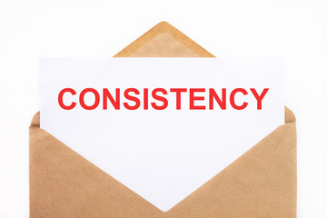 A white sheet with the text consistency lies in an open craft envelope on a white background with copy space. Business concept image