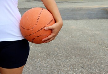 Girl in sports clothes holding basketball.
