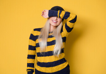 Shame. Close up young woman covering face with hands, model wearing woolen cap and sweater,...