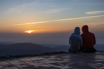 Couple watching the amazing sunrise from the top of La Mola Mountain in the Parc natural de Sant Llorenc del Munt i l'Obac, Valles Occidental, Catalonia, Spain. Copy space.