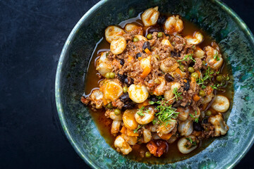 Modern style traditional slow cooked Mexican pozole rojo soup with ground minced beef, hominy maiz and beans served as top view in a Nordic design plate