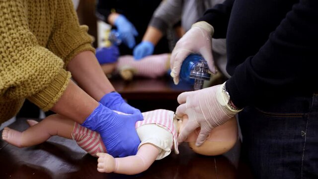 Instructor showing CPR on training doll. Woman performing CPR on baby training doll