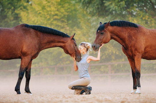 A girl stroking horses, kisses a horse in the face. A man with horses free.