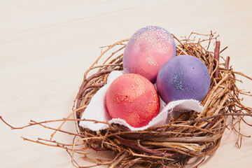 painted easter eggs and a decorative nest made of branches on a wooden table