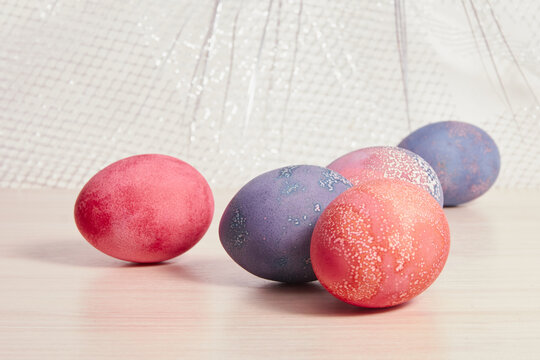 painted easter eggs and a decorative nest made of branches on a wooden table