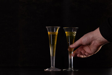 a man's hand raises one of two glasses of champagne