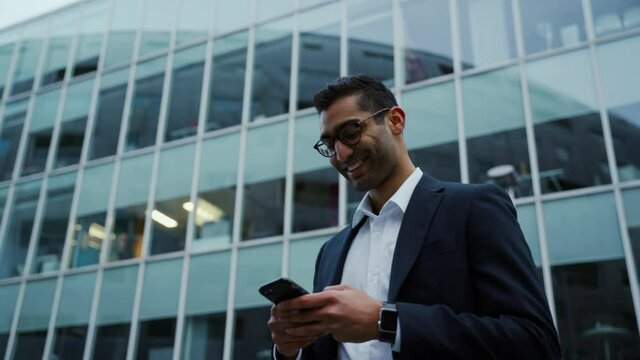 Mixed race business man typing on cellular device smiling after long day at work