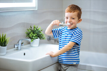 little boy brushing teeth in bathroom.