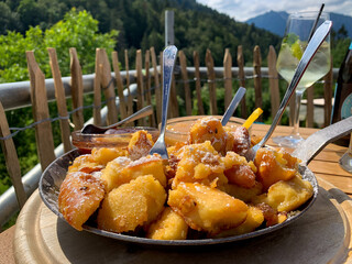 Traditional austrian bavarian dish kaiserschmarrn with applesauce and powdered sugar on iron pan in...