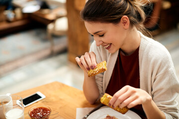 Young smiling woman enjoying in breakfast at home.