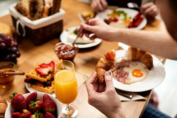 Close-up of man eating croissant with jam for breakfast.