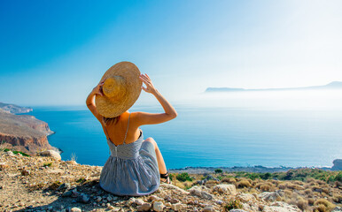 girl in hat and dress with sea coastline
