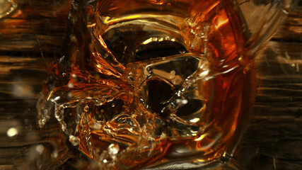 Top shot of ice cube splashing into glass of whisky