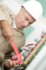 mature plumber using anjustable wrench