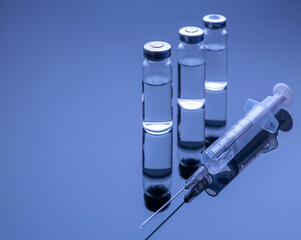 Vials with COVID-19 vaccine and a syringe with a needle for injection against coronavirus infection. Close-up. Fight against coronavirus concept