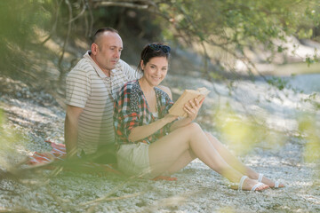 man and woman relaxing by lake