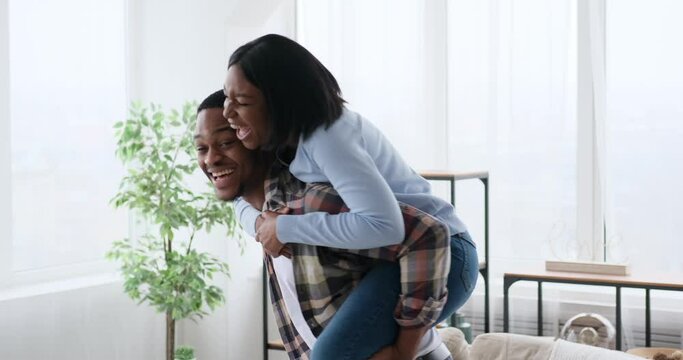 Cheerful couple laughing during a playful piggyback ride at home