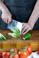 Close up of Chef cook hands chopping vegetables for traditional Asian cuisine with Japanese knife. Professional Sushi chef cutting cucumber for rolls.