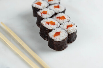 Sushi rolls prepared by professional asian chef with traditional Japanese ingredients. Salmon, rice, vegetables, sesame seeds. 