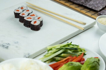 Sushi rolls prepared by professional asian chef with traditional Japanese ingredients. Salmon, rice, vegetables, sesame seeds. 