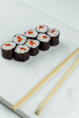 Sushi rolls prepared by professional asian chef with traditional Japanese ingredients. Salmon, rice, vegetables, sesame seeds. 