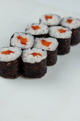 Sushi rolls prepared by professional asian chef with traditional Japanese ingredients. Salmon, rice, vegetables, sesame seeds. 