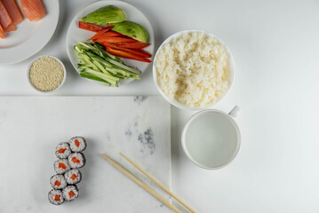 Sushi rolls prepared by professional asian chef with traditional Japanese ingredients. Salmon, rice, vegetables, sesame seeds. Sushi cooking and making concept