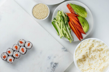 Sushi rolls prepared by professional asian chef with traditional Japanese ingredients. Salmon, rice, vegetables, sesame seeds. Sushi cooking and making concept