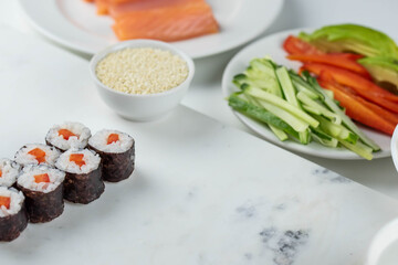 Sushi rolls prepared by professional asian chef with traditional Japanese ingredients. Salmon, rice, vegetables, sesame seeds. Sushi cooking and making concept