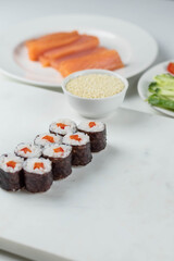 Sushi rolls prepared by professional asian chef with traditional Japanese ingredients. Salmon, rice, vegetables, sesame seeds. Sushi cooking and making concept
