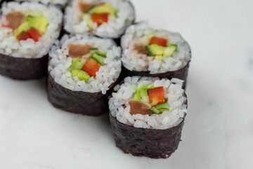 Sushi rolls prepared by professional asian chef with traditional Japanese ingredients. Salmon, rice, vegetables, sesame seeds. 