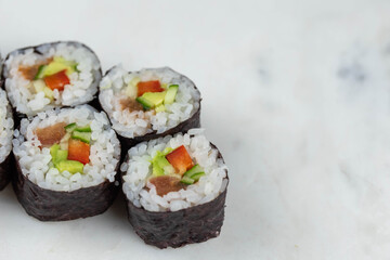 Sushi rolls prepared by professional asian chef with traditional Japanese ingredients. Salmon, rice, vegetables, sesame seeds. 