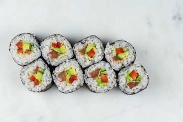 Sushi rolls prepared by professional asian chef with traditional Japanese ingredients. Salmon, rice, vegetables, sesame seeds. 
