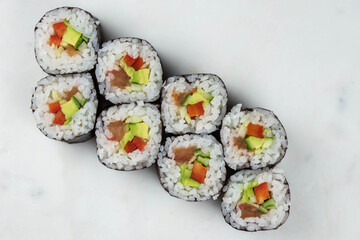 Sushi rolls prepared by professional asian chef with traditional Japanese ingredients. Salmon, rice, vegetables, sesame seeds. 