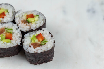 Sushi rolls prepared by professional asian chef with traditional Japanese ingredients. Salmon, rice, vegetables, sesame seeds. 