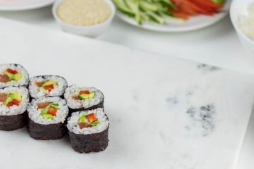 Sushi rolls prepared by professional asian chef with traditional Japanese ingredients. Salmon, rice, vegetables, sesame seeds. Sushi cooking and making concept