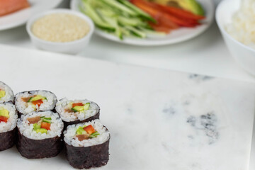 Sushi rolls prepared by professional asian chef with traditional Japanese ingredients. Salmon, rice, vegetables, sesame seeds. Sushi cooking and making concept
