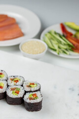 Sushi rolls prepared by professional asian chef with traditional Japanese ingredients. Salmon, rice, vegetables, sesame seeds. Sushi cooking and making concept