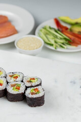 Sushi rolls prepared by professional asian chef with traditional Japanese ingredients. Salmon, rice, vegetables, sesame seeds. Sushi cooking and making concept