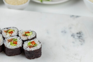 Sushi rolls prepared by professional asian chef with traditional Japanese ingredients. Salmon, rice, vegetables, sesame seeds. 