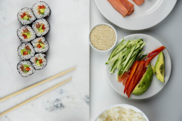 Sushi rolls prepared by professional asian chef with traditional Japanese ingredients. Salmon, rice, vegetables, sesame seeds.  Sushi cooking and making concept