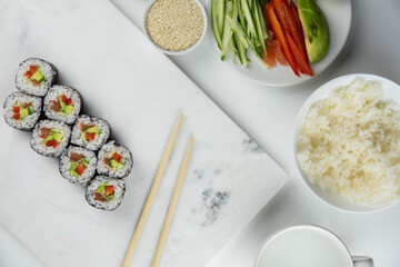 Sushi rolls prepared by professional asian chef with traditional Japanese ingredients. Salmon, rice, vegetables, sesame seeds.  Sushi cooking and making concept
