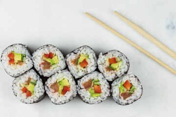 Sushi rolls prepared by professional asian chef with traditional Japanese ingredients. Salmon, rice, vegetables, sesame seeds. 