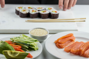 Sushi rolls prepared by professional asian chef with traditional Japanese ingredients. Salmon, rice, vegetables, sesame seeds. 